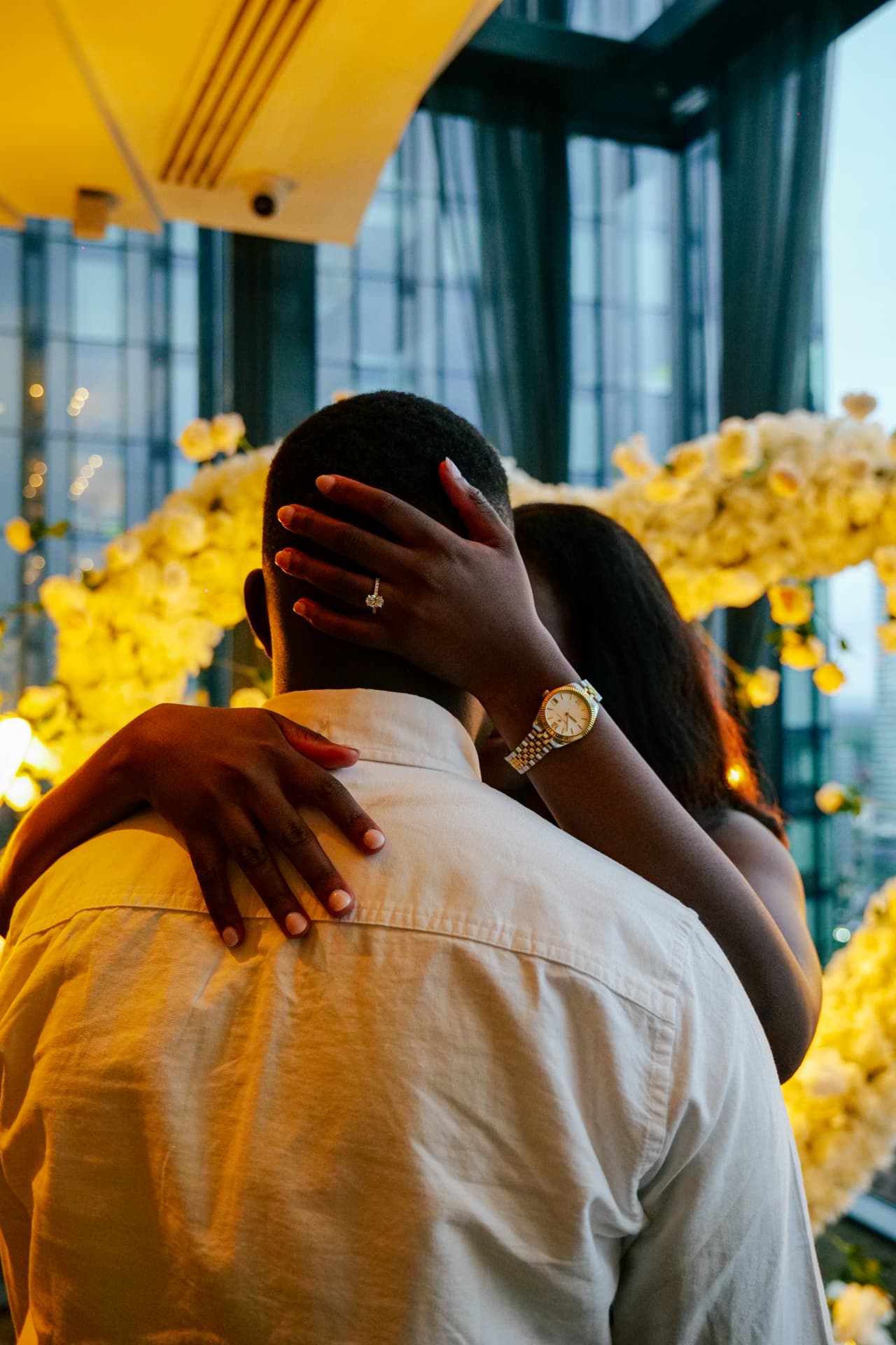 Martha embracing Emmanuel, her engagement ring catching the light